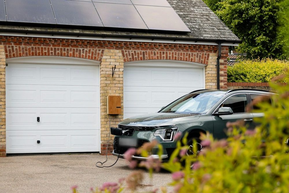 Rodinný dům s fotovoltaickými panely na střeše garáže, u vjezdu se nabíjí elektromobil